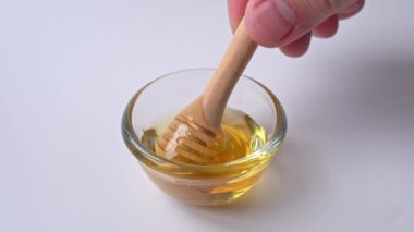 Bal damlıyor, cam kaseye bal damlatıyor. Yakın plan. Ahşap bal kaşığından batırılan sağlıklı organik bal, yakın plan. 4K UHD video görüntüleri.