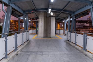 Alacakaranlıkta modern kentsel yaya geçidi, asgari sayıda insan ve hareketli bir şehir manzarasında aydınlatma işareti.