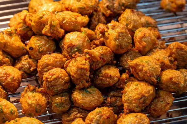 Sıcak yağda kızaran çıtır altın sebzeli börekler kalabalık bir sokak gıda pazarında.