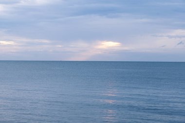 Ufuk sakin suların üzerinde uzanıyor, yumuşak dalgalar gökyüzünü yansıtıyor. Güneş batarken yumuşak mavi ve gri renkler karışıyor. Rahatlamak için mükemmel sakin bir atmosfer yaratıyor..