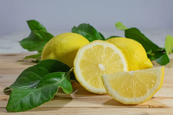 Tahta bir masada yaprakları sıralanmış doğal, taze ve sağlıklı limonlar.