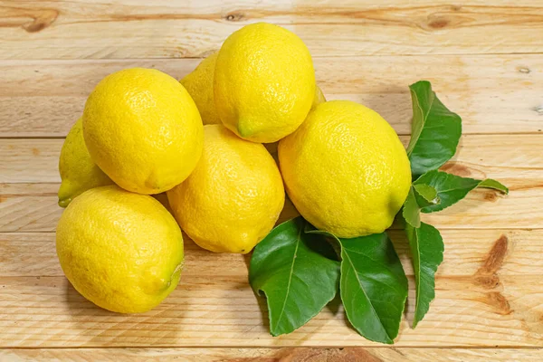 Tahta bir masada yaprakları sıralanmış doğal, taze ve sağlıklı limonlar.