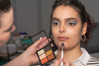 Profesyonel makyöz, güzellik salonunda genç bir kadını uyduruyor.