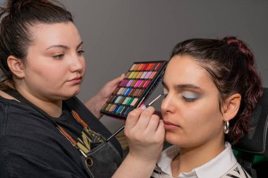 Güzellik salonunda genç bir kadının gözlerini yapan profesyonel bir makyöz.