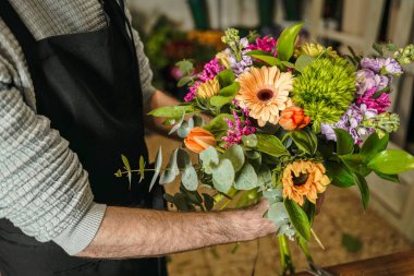Çiçekçi, Gerberas, laleler ve okaliptüs ile canlı bir buket hazırlıyor.