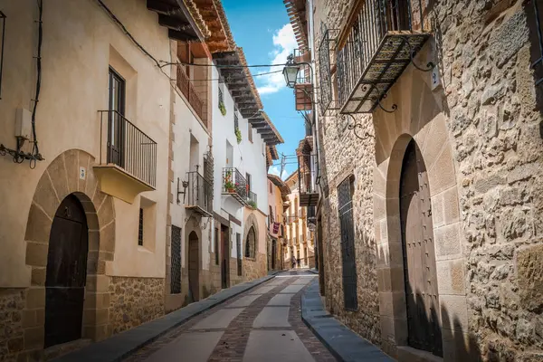 stock image Charming narrow cobblestone street in a picturesque Mediterranean village, featuring traditional stone houses and vintage street lamps adorning the facades. 