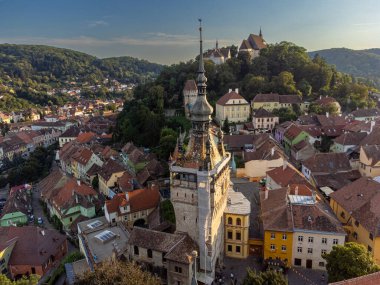 Saat kulesi ve tepenin, kalenin ve eski binaların yer aldığı tarihi bir Romanya kenti olan Sighisoara 'nın insansız hava aracı manzarası. Turizm ve mimari temalar için mükemmel.