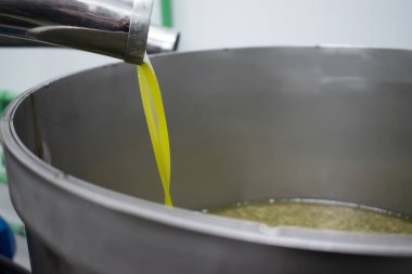  Modern bir fabrikada ekstra bakir zeytinyağı özütü. Metal bir konteynıra dökülen yağın ayrıntıları.