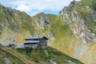 Bir yaz günü, arkasında Karpat Dağları olan dağın tepesindeki yalnız bir dağ kulübesinin ayrıntıları. Romanya 'da Transfagarasan Yolu.