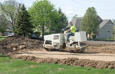 Dayton, Ohio - 16 Nisan 2024: İnşaat işçisi gelişmekte olan bir konut projesinde toprağı sıkıştırmak için çifte davul çalar. 