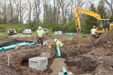 Dayton, Ohio - April 17, 2024: Dayton Realtors report residential condo sales have increased 5.46% since March 2023. Shown here is excavation crew laying drainage pipe for new condo complex. clipart