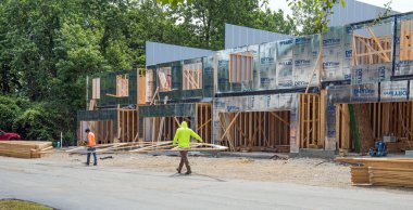 Dayton, Ohio - 18 Haziran 2024: Göçmen inşaat işçileri yeni konut geliştirme çatısı olarak kullanmak üzere yeni çatı kirişini yerleştirdiler.