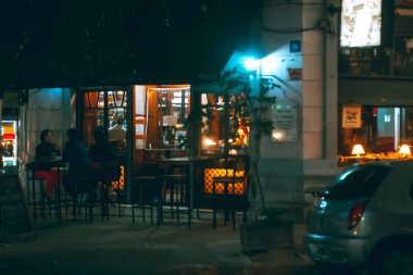 Şehrin gece manzarası ve kafedeki insanlar. 