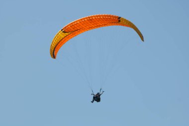 Gökyüzünde paraşütle paraşütle atlayan biri.