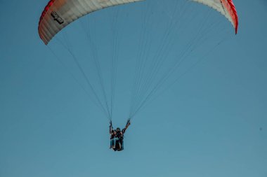 Gökyüzünde paraşütle paraşütle atlayan biri.