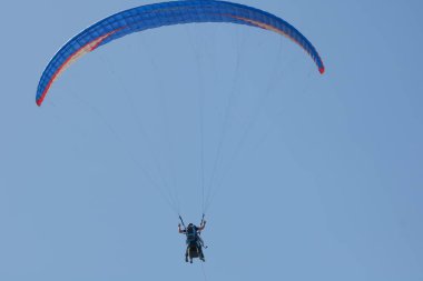 Gökyüzünde paraşütle paraşütle atlayan biri.