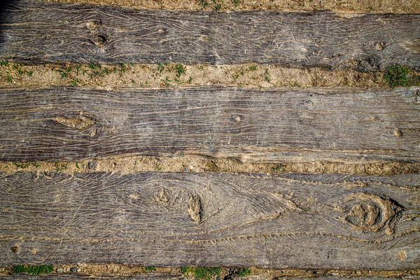 a wooden surface with a few scratches and small grass