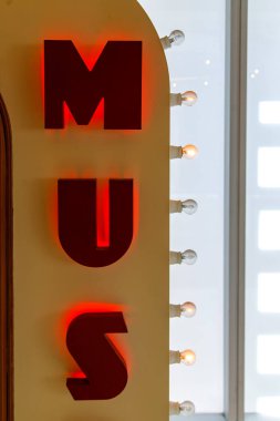 Duvarda kırmızı neon ışığı, MUS mesajı.