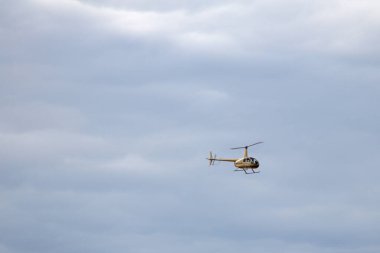 Bulutlu gökyüzünde uçan helikopterin gündüz görüntüsü