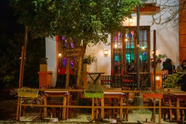 İnsanlar sokakta açık bir kafede oturuyorlar. 