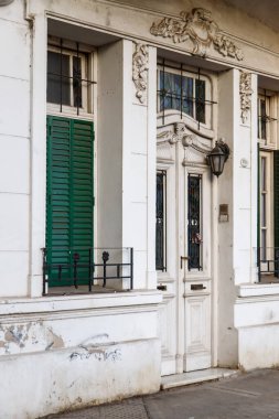 Süslü beyaz bina cephesinde yeşil kepenkler