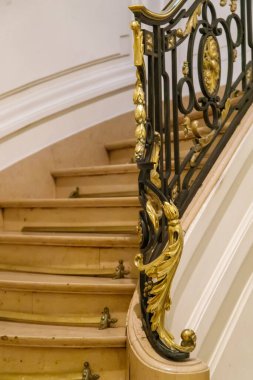 Eğri büğrü ahşap merdivenlerin yanında süslü altın parmaklıklar