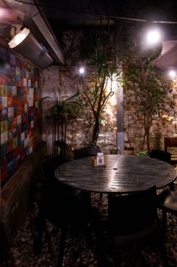 Yuvarlak masa, dışarıdaki sıcak aydınlatma altında sandalyelerle çevrili.