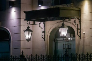 Aydınlatılmış fenerler zarif bir binanın girişinde asılı.