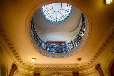 Dairesel tavan penceresi ve balkon korkulukları olan süslü bir tavan.