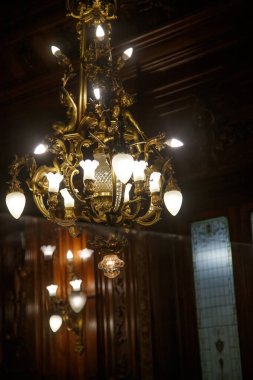 Zarif ahşap odada asılı altın bir avize.