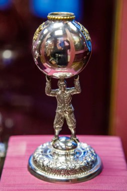 Gümüş kupa. Parlak küreyi tutan bir sporcu.