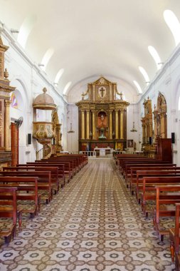 Güneş ışığıyla süslenmiş kilise iç tarafında ahşap sıralar var.