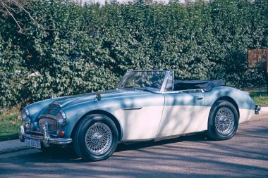 Klasik mavi beyaz üstü açık araba çitin yanına park edilmiş.