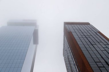 Uzun, modern gökdelenler kalın sisin içinde kayboluyor.