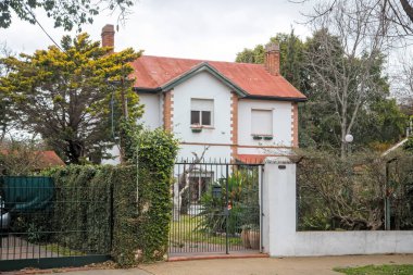 Demir kapının arkasındaki büyüleyici beyaz ev ağaçları kuşattı.