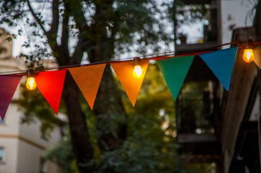 Dışarıda parlayan ışıkların arasında asılı renkli üçgen bayraklar