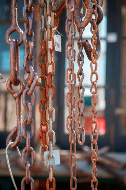 Paslı metal zincirler dışarıda güneş ışığında asılı.