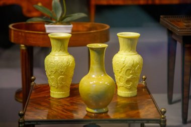 Tahta masada duran üç sarı seramik vazo.