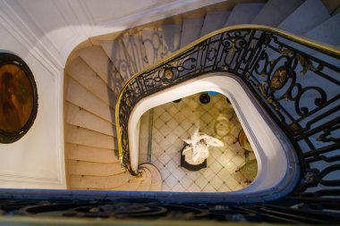 Süslü metal korkulukların etrafında dönen sarmal merdiven.