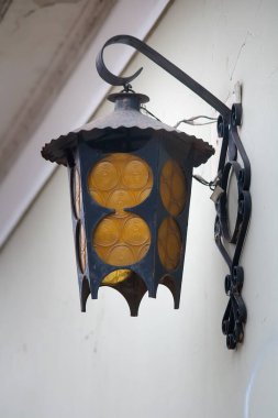 Beyaz duvara asılı klasik metal fener.