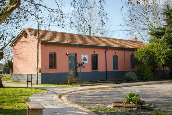 Yeşil ağaçların arasında mavi panjurlu pembe ev