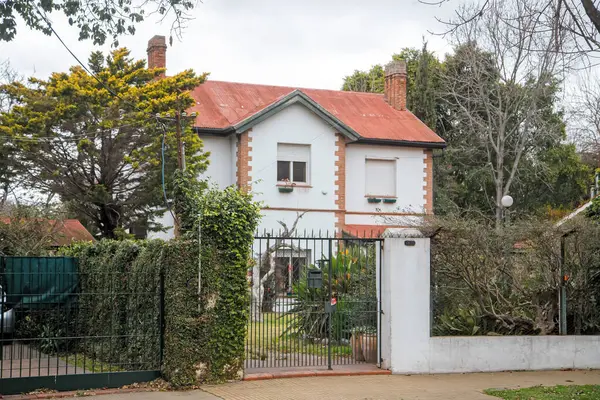 Demir kapının arkasındaki büyüleyici beyaz ev ağaçları kuşattı.