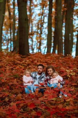 Bir aile, sonbaharın ortasında iki küçük ikiz kız kardeşle yürüyor.; 