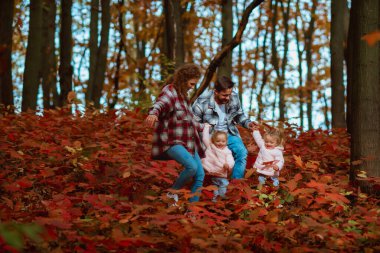 Bir aile, sonbaharın ortasında iki küçük ikiz kız kardeşle yürüyor.; 