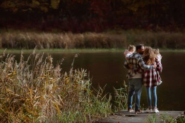 Bir aile, sonbaharın ortasında iki küçük ikiz kız kardeşle yürüyor.; 