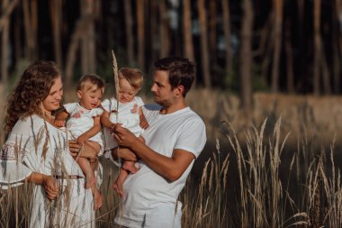 Bir aile doğanın ortasında iki çocuk ve ikiz kız kardeşle yürür.;