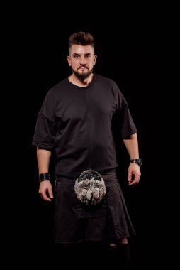 Stüdyoda siyah bir arkaplanda İskoç omurgası takan erkek portresi. Kameraya bakın.