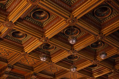 Yapıldığı dekor ve malzeme parçası; avizelerin asılı olduğu ahşap tavandaki simetrik dekoratif desenler