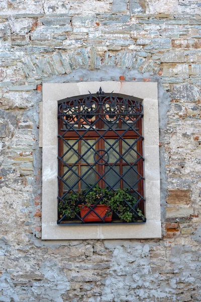 建物のファサードの装飾の一部とそれが構築されている材料 黒い鉄の棒の後ろに窓のある古い壁 — ストック写真