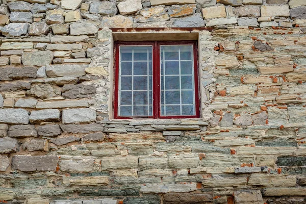 Part of the decoration of the facade of the building and the material from which it is built;  old stone house and window